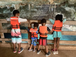 A group of kids wearing an orange color safety vest