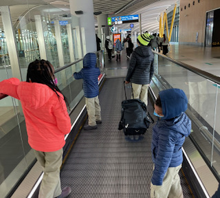Kids standing on the escalator at the airport