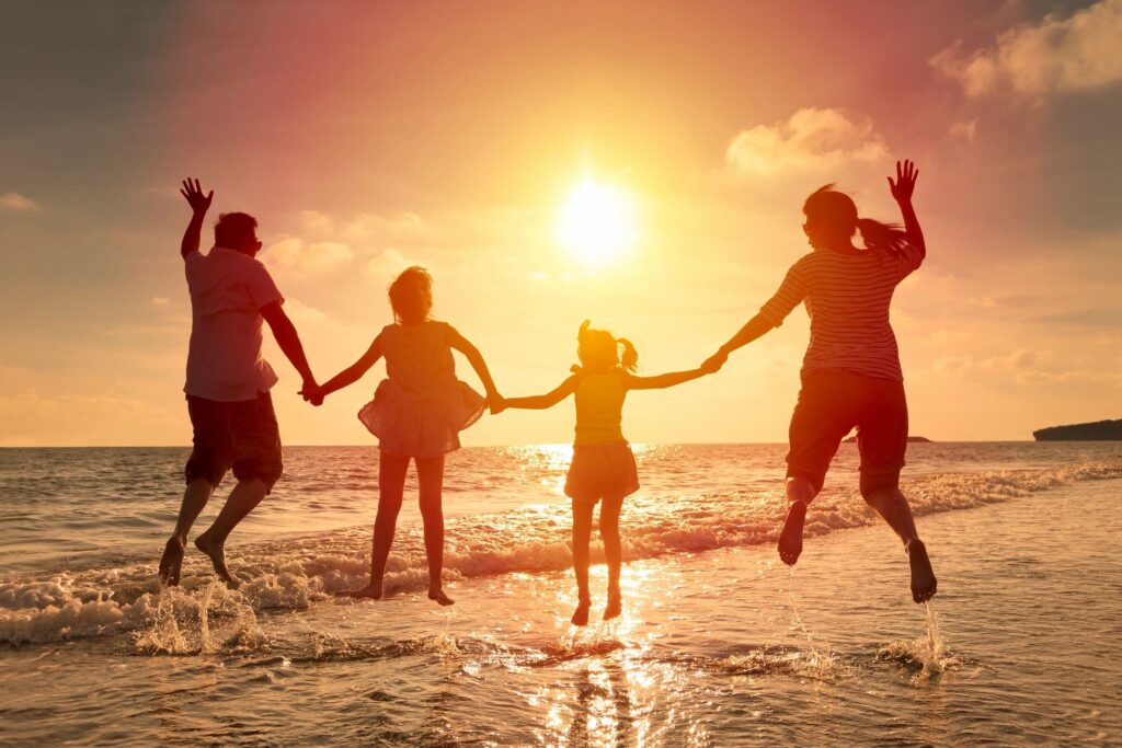 The silhouette of a family jumping on a beach